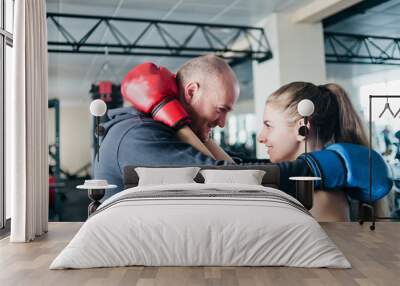 Loving couple embraces in boxing gloves and looks at each other's eyes in the gym. Wall mural