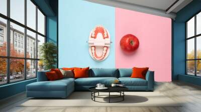 Model of human jaw with apple on pink blue pastel background. Dental care. Creative flat lay. Top view Wall mural