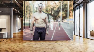 Muscular male runner with a naked torso at the stadium. Healthy lifestyle Wall mural