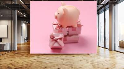 Piggy bank on stack of gift boxes. Pink pastel  background Wall mural