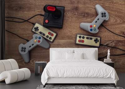 Retro joysticks and gamepads on a wooden floor. Top view Wall mural