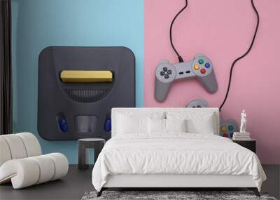 Retro video game console with joysticks on pink blue background. Top view Wall mural