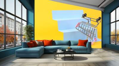 Shopping trolley on stairs, yellow background. Concept art, minimalism Wall mural