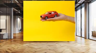 Toy car on the palm of a woman's hand on a yellow background. Protection, insurance auto concept Wall mural