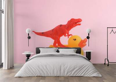 Toy red dinosaur tyrannosaurus rex with rubber duck on pink background. Minimalism creative layout Wall mural