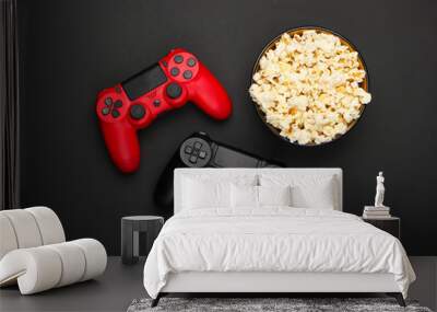 Two gamepads and a bowl of popcorn on black background. Gaming, leisure and entertainment concept. Top view Wall mural