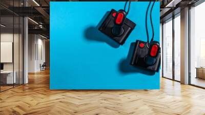 Two retro joysticks on a blue background with a shadow. Retro gaming. Top view Wall mural