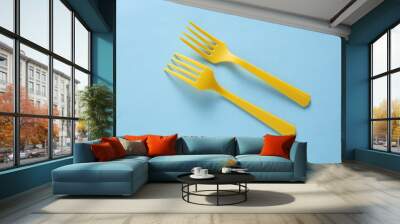 Yellow Plastic forks on blue background. Top view Wall mural