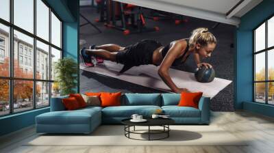 Young attractive sport woman in sportswear is practicing push-ups with a medicine ball in the gym. Functional Training Concept Wall mural