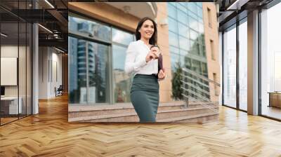 young purposeful professional business woman wearing a blouse and a skirt leaving the business cente Wall mural