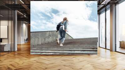 Young woman student climbs the stairs up Wall mural