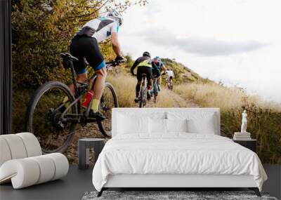 group athletes cyclists riding sports bicycle on gravel road with bushes on side in cross-country cycling competition Wall mural