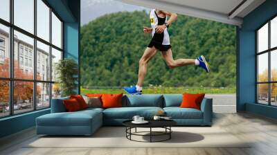 leading athlete runner running marathon race in background of mountains and forests Wall mural