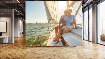 Relaxed senior couple sailing private yacht at sunset Wall mural