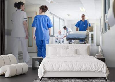 male nurse pushing stretcher gurney bed in hospital corridor with doctors & senior female patient Wall mural