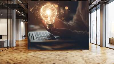 photograph of a person sitting at the laptop and holding a white glowing light bulb-shape. Air around the shape is full of white glowing dust. Close-up to the hands. The style is modern digital, the Wall mural