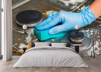 Female hand cleaning gas stove using sponge and detergents. Cleaning a gas stove with kitchen utensils, household concepts, or hygiene and cleaning Wall mural