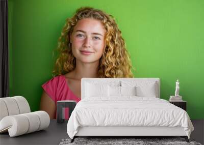 Joyful Woman with Curly Blonde Hair in Pink Dress Against Vivid Green Background Wall mural