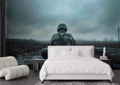 Somber Soldier Reflecting Alone on Battlefield in Overcast Weather, Symbolizing War Remnants and Loss Wall mural