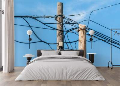 Old retro style wooden pole with many electric supply wires or cables against blue sky Wall mural