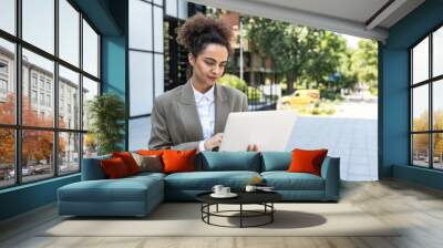 Portrait of young successful businesswoman office worker using laptop computer outside office building in formal wear. Professional female business person working outdoor online, checking information Wall mural