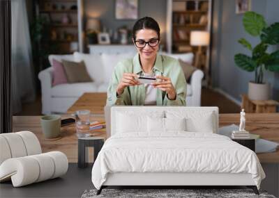 Young business woman using break from working in home office for paying home finances or online shopping with credit card and laptop computer. Confident female pay her online order. Wall mural