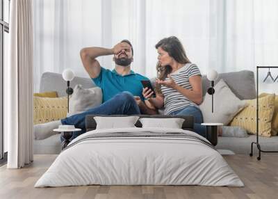 Young couple arguing about text messages on the boyfriends phone where girlfriend is jealous for finding the communication with other girl Wall mural