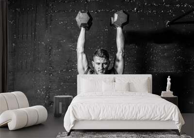 Young strong fit muscular sweaty man with big muscles strength cross workout training with dumbbells weights in the gym dark image with shadows real people black and white Wall mural