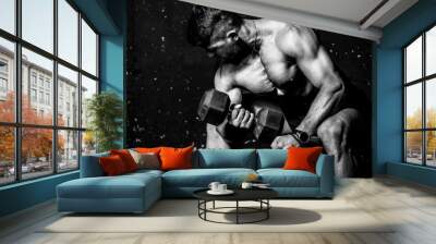 Young strong muscular sweaty fit man biceps muscle workout cross training with heavy dumbbell in the gym dark image with shadows real people black and white Wall mural