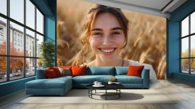 Happy beautiful woman smiling at camera in a wheat field - Delightful female enjoying summertime sunny day outside - Wellbeing concept with confident girl laughing in the nature Wall mural