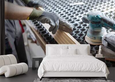 Carpenter with grinder. Man grinding planks of wood for home construction Wall mural