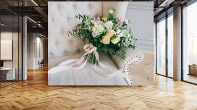 Rustic wedding bouquet with creamy roses and white carnations on a luxury cream sofa. Close-up. Side view Wall mural