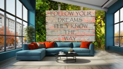 Follow Your Dreams They Know The Way motivational quote written on old vintage board sign in the forrest, with sun rays in background. Wall mural