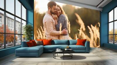 Beautiful agricultural field. Cheerful lovely young couple having a rest outdoors together Wall mural