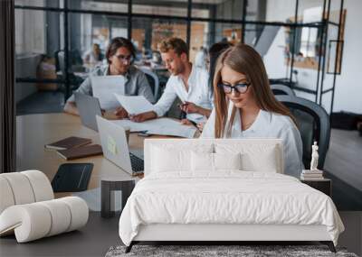 Blonde girl reads document. Young business people in formal clothes working in the office Wall mural