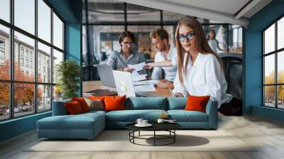 Blonde looks into the camera. Young business people in formal clothes working in the office Wall mural