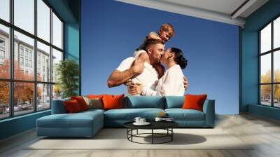 Bright blue sky, against it. Mother and father are with son outdoors on the field Wall mural