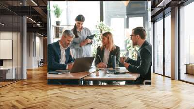 Busy workers are by the table. Group of business people are in the modern office Wall mural