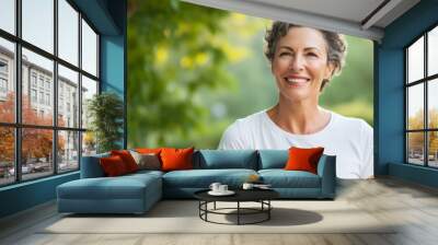 Close up of a 50s middle age woman smiling and wearing a white t-shirt on a outdoor background Wall mural