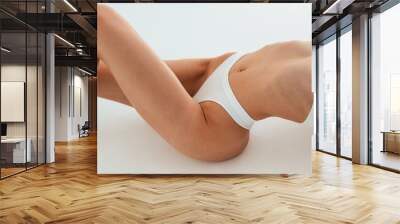 Close up view of belly, on the floor. Young woman with slim body type is in fitness clothes in the studio Wall mural