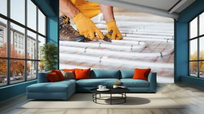 Close up view. Worker in yellow colored uniform installing underfloor heating system Wall mural