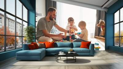 Construction toys. Father is playing with two little boys on the floor Wall mural