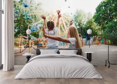 Eating ice cream. Cheerful little girl her mother have a good time in the park together near attractions Wall mural