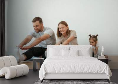 Family of mother, father and daughter are doing yoga at home Wall mural