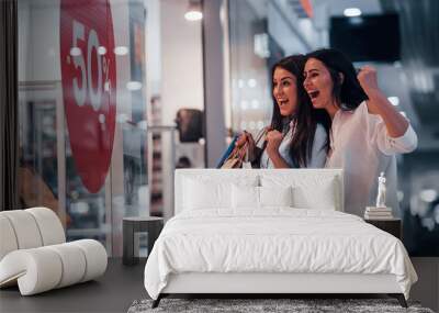 Feeling excited. Two young women have a shopping day together in the supermarket Wall mural