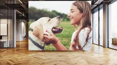 Frame with a beautiful girl with a beautiful dog in a park on green grass. Wall mural