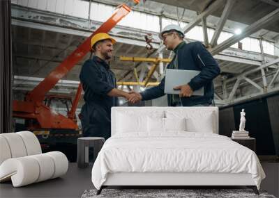 Friendly handshake. Two male factory workers are in the warehouse Wall mural