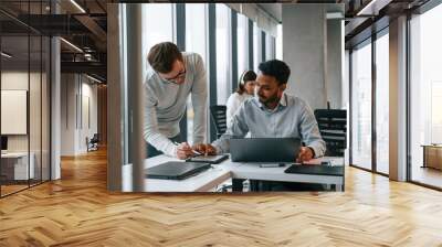 Guys are talking with each other. Men and woman are working in the office together Wall mural