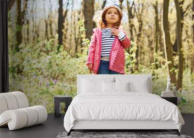 Happy little girl in blue hat have walk in spring forest at daytime Wall mural