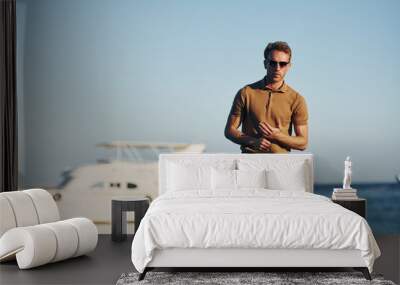 In sunglasses. Young man is outdoors at sunny daytime. Concept of vacation Wall mural